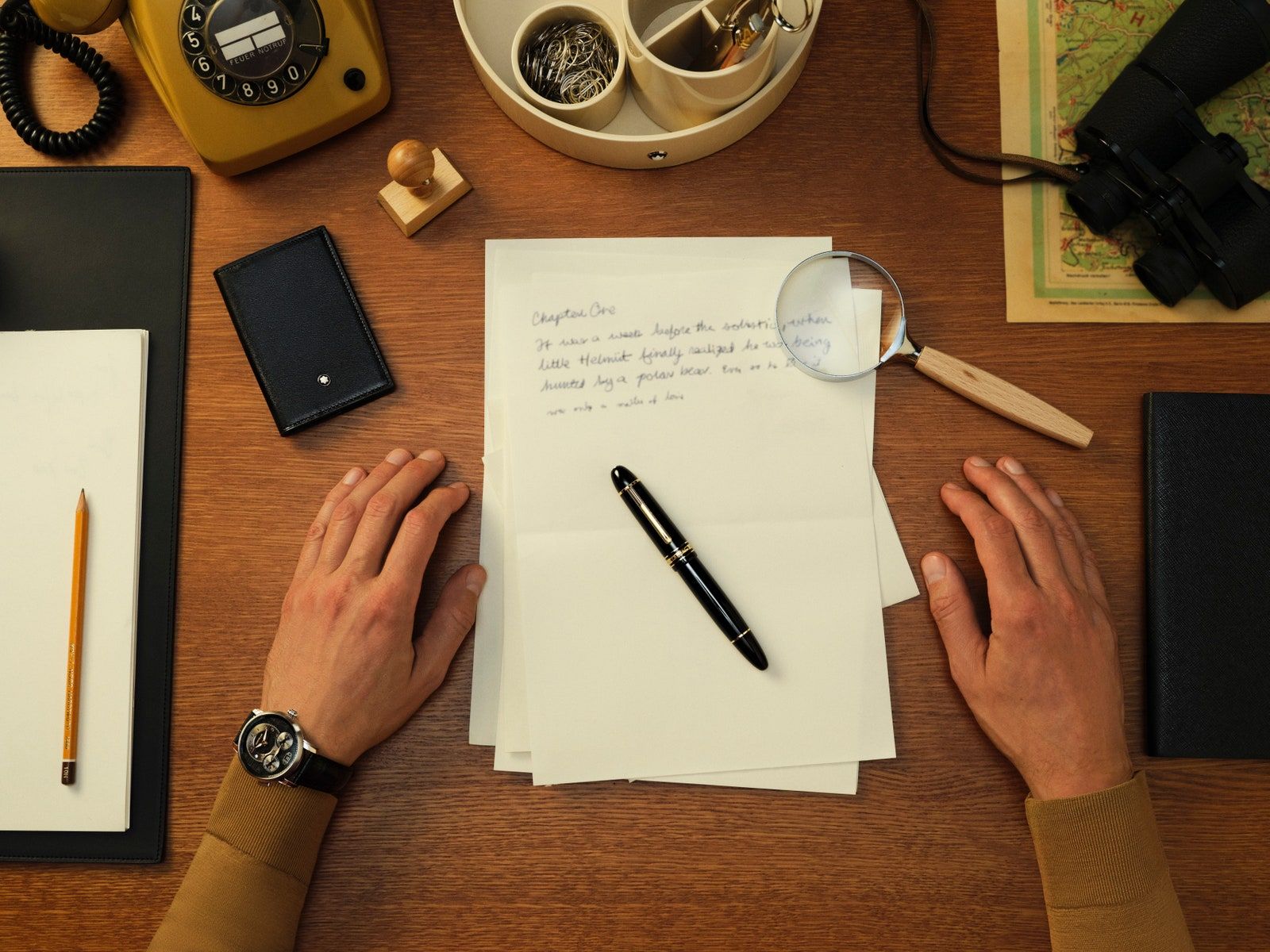 Image may contain Pen Wristwatch Desk Furniture Table Person Writing Camera Electronics Text and Mobile Phone